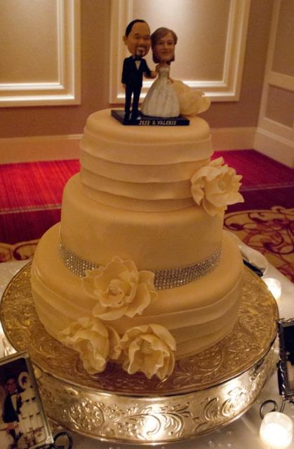 3 tier round white wedding cake with bride and groom custom bobble head toppers.JPG